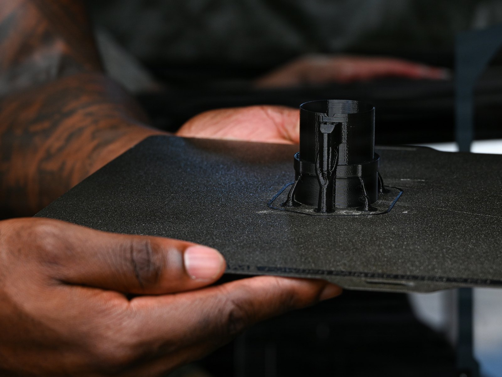 A U.S. Marine holds a freshly 3D-printed part on its build plate