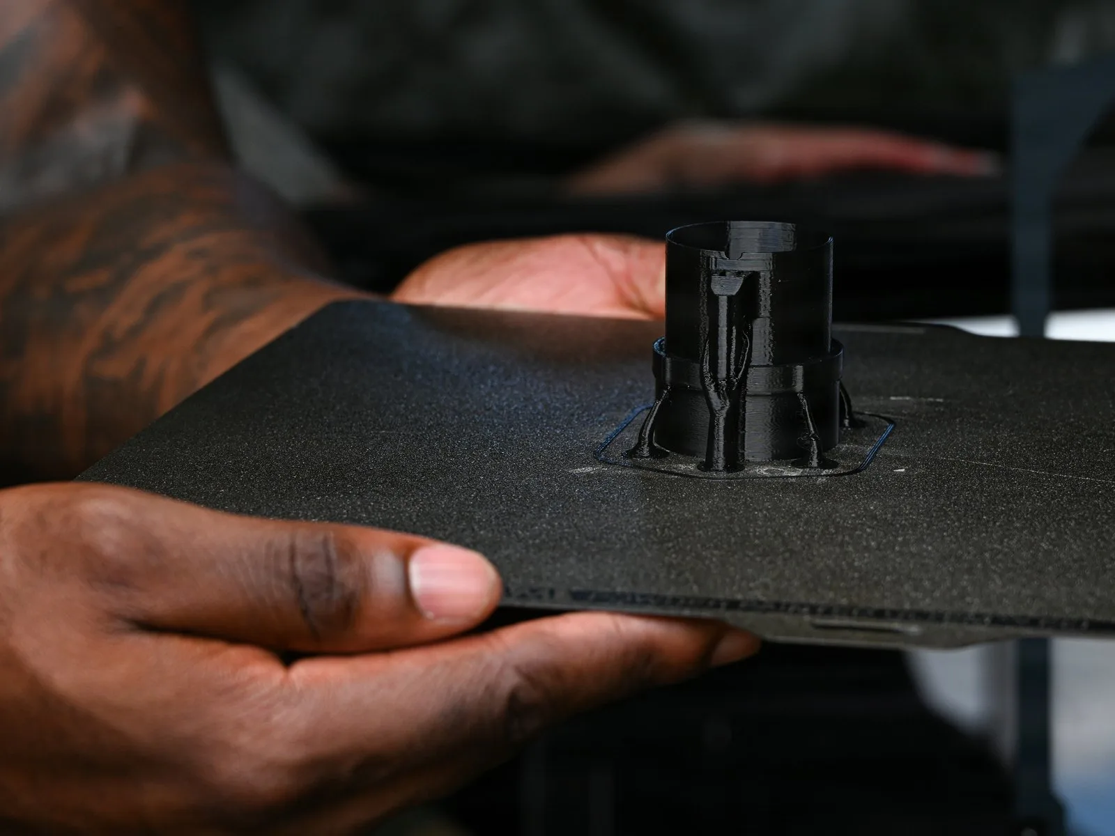 A U.S. Marine holds a freshly 3D-printed part on its build plate